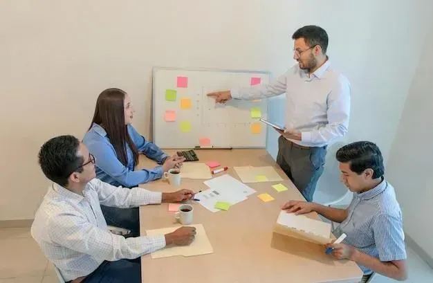 A man pointing at a whiteboard with people around it